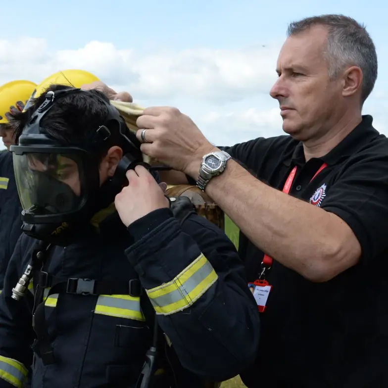 Instructor fitting trainee with breathing apparatus